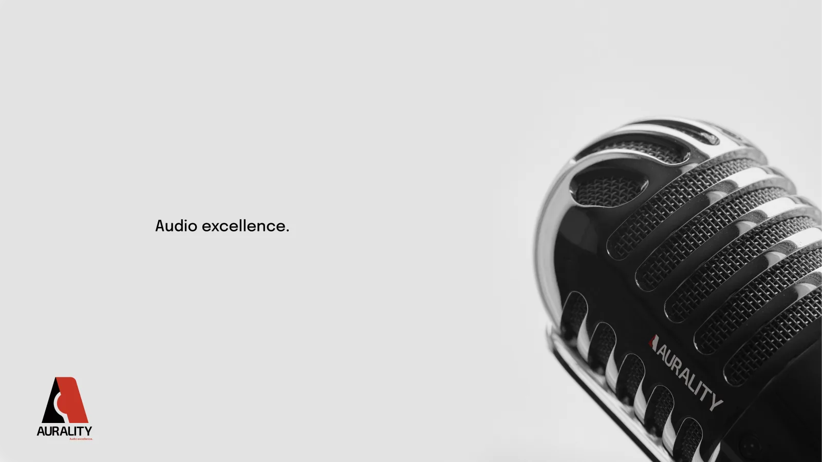 An Aurality ad: a chrome-and-black retro microphone entering from the right on a light-gray ground, with ‘Audio excellence.’ set center-left and the AURALITY lockup.